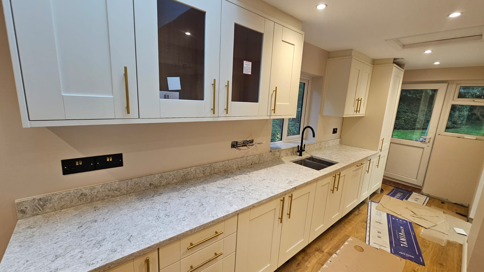 Newly fitted shaker kitchen with cream cabinetry, brass handles and quartz stone worktops