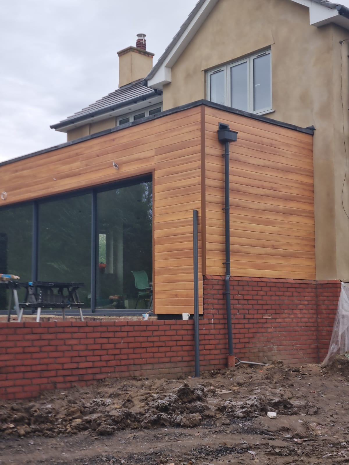 Completed timber-clad single-storey rear house extension with large picture windows