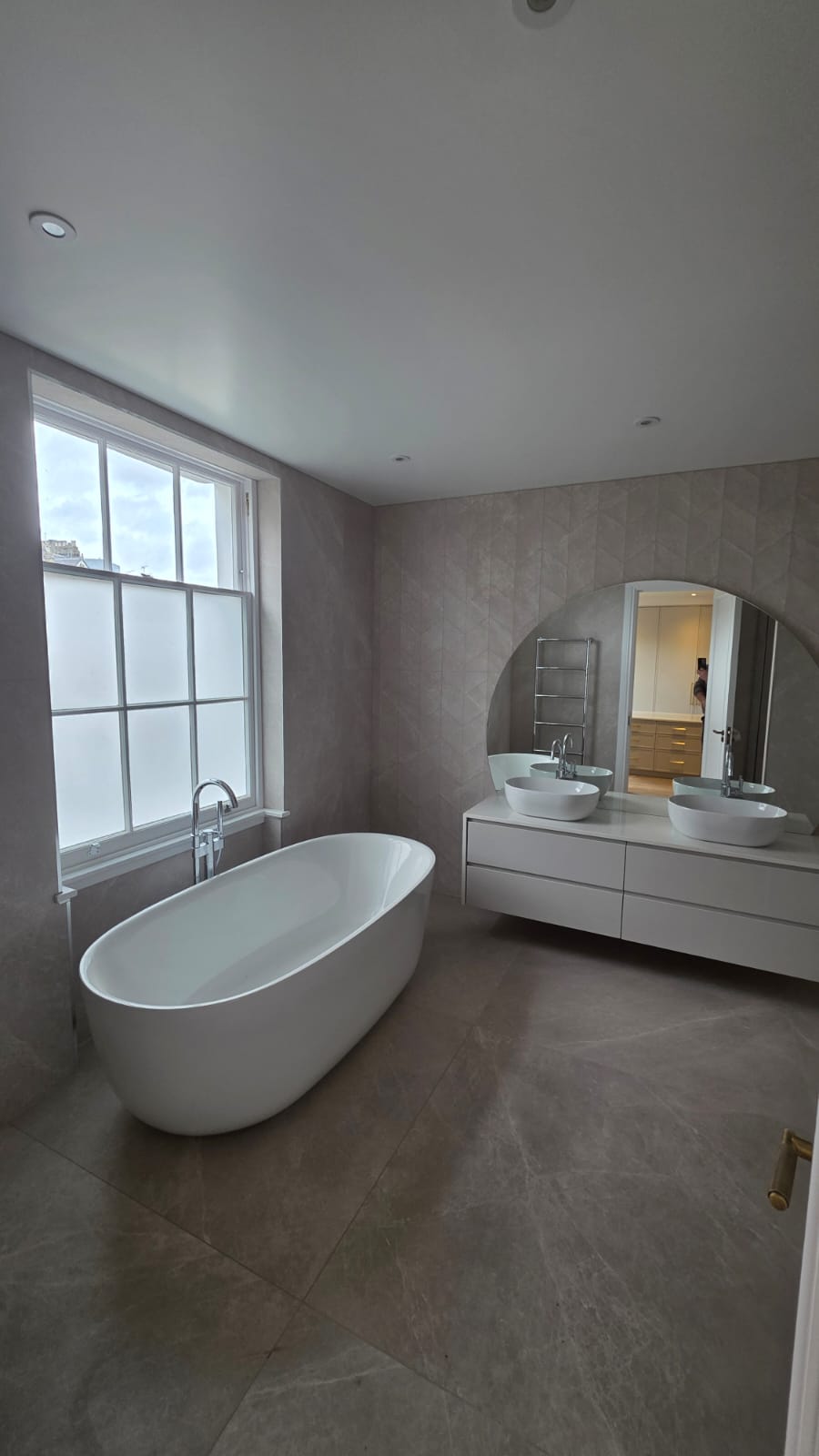 Completed luxury bathroom with freestanding bath, twin vanity and full-height tiling